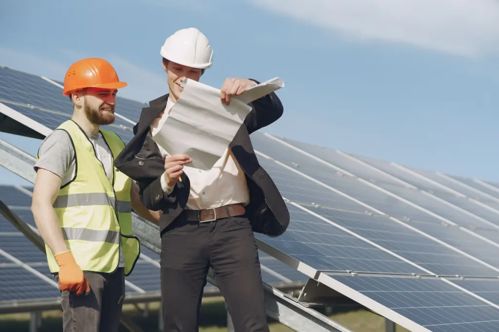 At a solar power field, a technical expert and a businessman are conducting a review.