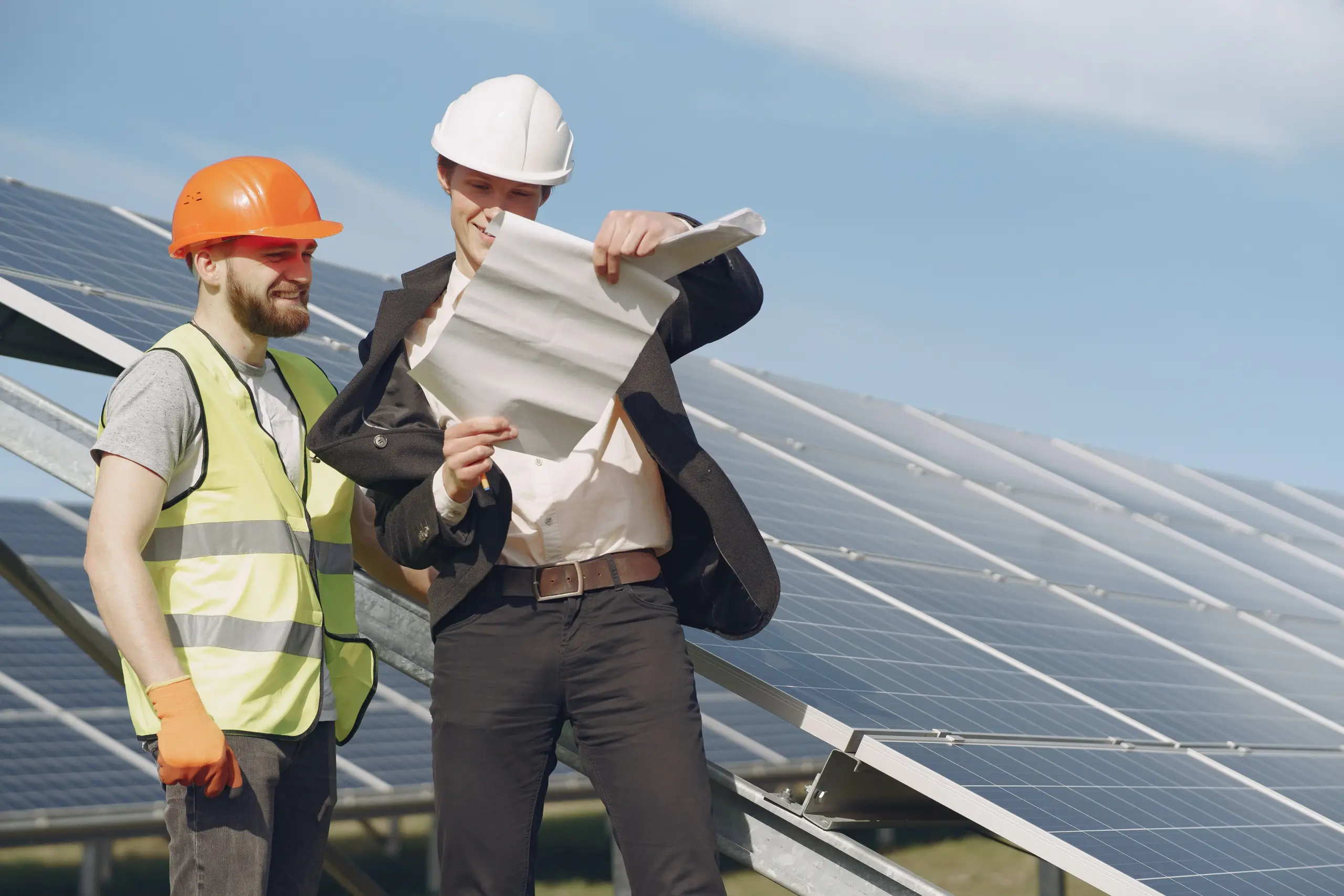 At a solar power field, a technical expert and a businessman are conducting a review.