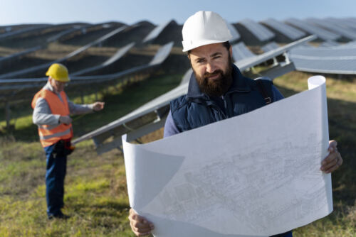 Two solar energy technicians conducting checks on a field of photovoltaic panels.